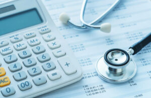 Une calculatrice et une stéthoscope sur un bureau pour prendre une mutuelle collective pour une PME.